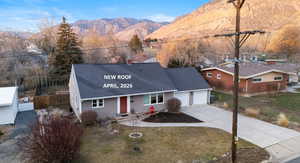 View of front facade featuring roof with shingles, concrete driveway, a mountain view, a garage, and a chimney