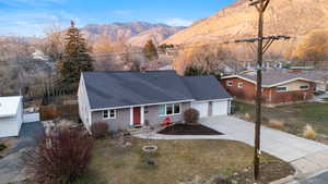 Single story home with a shingled roof, a mountain view, driveway, a garage, and a chimney
