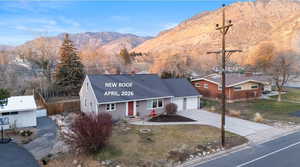 View of front of property with driveway, a mountain view, an attached garage, and roof with shingles