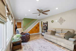 Living area featuring light wood finished floors, recessed lighting, a ceiling fan, and stairway