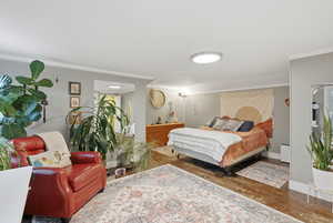 Bedroom featuring ornamental molding and wood finished floors