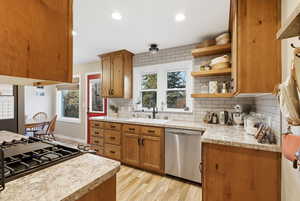 Kitchen featuring brown cabinets, light wood-type flooring, light countertops, appliances with stainless steel finishes, and recessed lighting