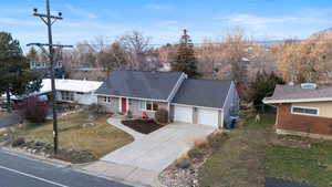 View of front of home featuring driveway, a shingled roof, an attached garage, and a front yard