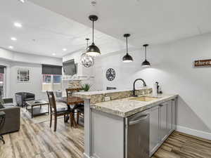 Kitchen with a peninsula, decorative light fixtures, dishwasher, gray cabinetry, and light wood-style floors