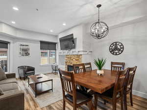 Dining room with a stone fireplace, recessed lighting, wood finished floors, and a chandelier