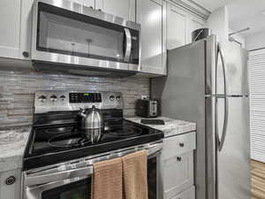 Kitchen with appliances with stainless steel finishes and tasteful backsplash