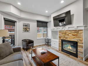 Living area featuring a stone fireplace, wood finished floors, and recessed lighting