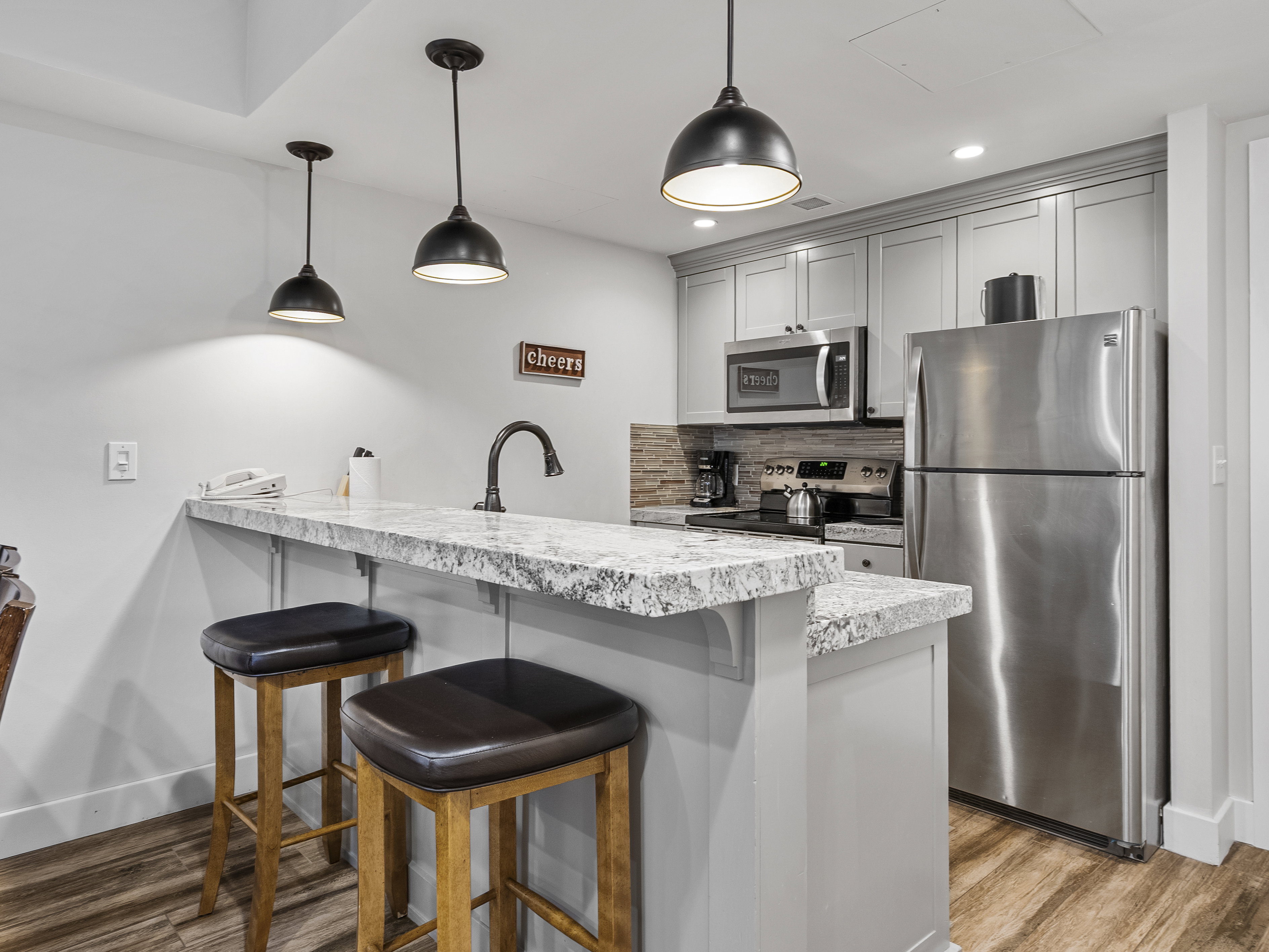 Kitchen with a kitchen breakfast bar, appliances with stainless steel finishes, light stone counters, hanging light fixtures, and recessed lighting