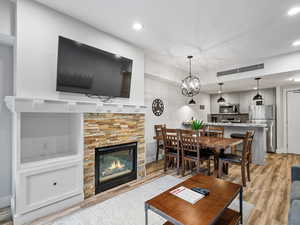 Living area with a fireplace, light wood finished floors, a chandelier, and recessed lighting