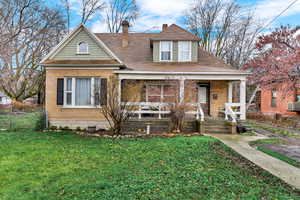 View of front of home with a porch, a chimney, and a front lawn