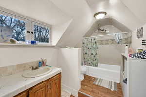 Full bath featuring vanity, shower / bath combo, light wood-style flooring, and vaulted ceiling