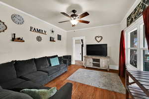 Living room featuring ornamental molding, hardwood / wood-style flooring, and ceiling fan