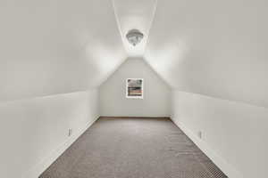 Additional living space with carpet floors and vaulted ceiling