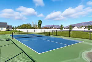View of tennis court with community basketball court and a mountain view