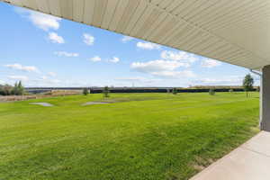 View of grassy yard featuring a patio