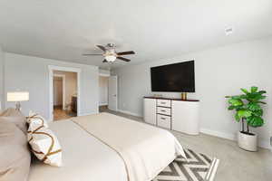 Bedroom with ensuite bath, ceiling fan, and light colored carpet