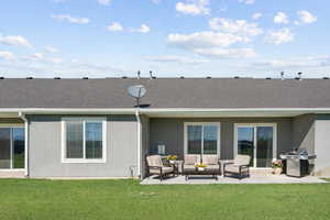 Back of property featuring stucco siding, outdoor lounge area, a patio area, and a lawn