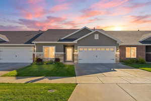 Craftsman house featuring an attached garage, a lawn, driveway, roof with shingles, and stucco siding
