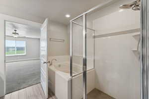 Full bath with a ceiling fan, a stall shower, a garden tub, recessed lighting, and light wood-style floors