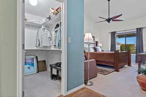 Bedroom with light colored carpet, vaulted ceiling, a ceiling fan, and a textured ceiling