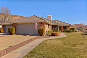 View of front of home with a mountain view, a front lawn, brick siding, a tiled roof, and a chimney