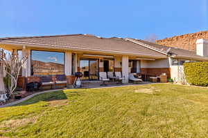 Rear view of house with brick siding, a patio area, a lawn, and an outdoor living space