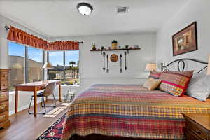 Bedroom with wood finished floors and a textured ceiling