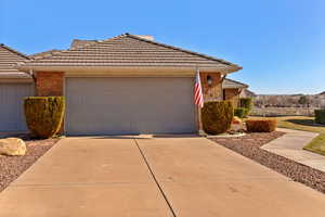 View of front of property featuring concrete driveway, a tile roof, and brick siding