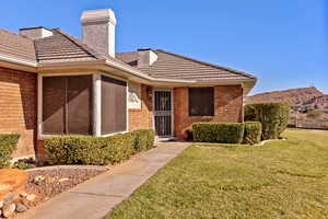 Doorway to property featuring brick siding, a lawn, a chimney, a tiled roof, and a mountain view