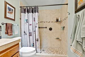 Bathroom featuring tiled shower, vanity, and a textured ceiling