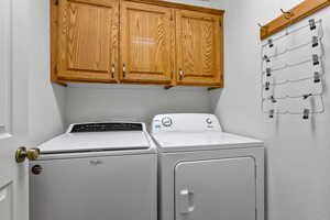 Washroom featuring cabinet space and washing machine and clothes dryer