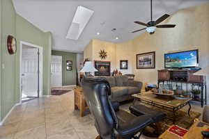 Living room featuring a skylight, light tile patterned floors, high vaulted ceiling, recessed lighting, and ceiling fan