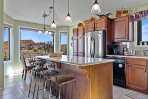 Kitchen featuring freestanding refrigerator, decorative backsplash, decorative light fixtures, a breakfast bar area, and dishwasher