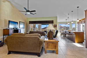 Living room featuring ceiling fan, high vaulted ceiling, and light tile patterned floors