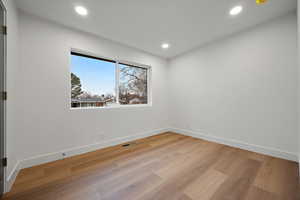 Empty room with light wood-style floors and recessed lighting