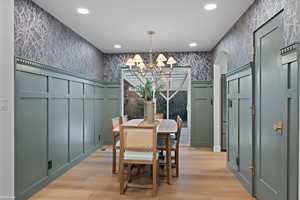 Dining space with recessed lighting, a chandelier, light wood-style flooring, a decorative wall, and wallpapered walls