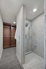 Full bath with a marble finish shower, dark tile patterned floors, and recessed lighting