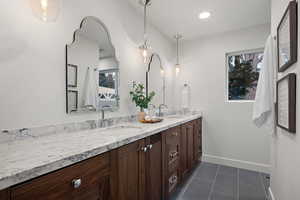 Bathroom featuring double vanity and dark tile patterned floors