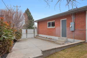 Back of house featuring a gate, brick siding, and entry steps