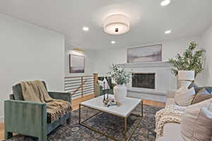 Living room featuring wood finished floors, recessed lighting, and a brick fireplace