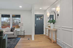 Foyer with a decorative wall, light wood-type flooring, and recessed lighting