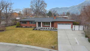 Ranch-style house featuring a porch, concrete driveway, a mountain view, a chimney, and a garage