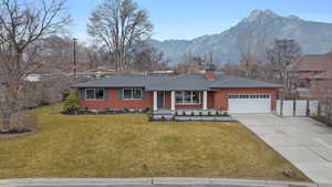 Ranch-style house featuring a porch, driveway, a chimney, a garage, and a mountain view