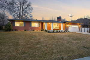 View of front of property with a front lawn, brick siding, concrete driveway, and a chimney