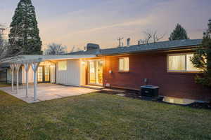 Rear view of house featuring a lawn, board and batten siding, a patio area, brick siding, and french doors