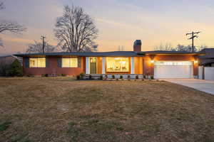 View of front of house featuring driveway, a porch, a front lawn, and a chimney