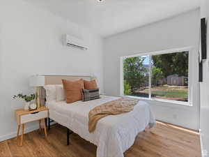 Bedroom featuring light wood-style floors and a wall mounted air conditioner