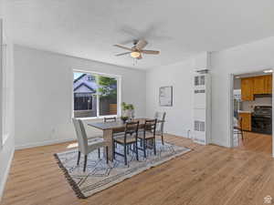 Dining space with a heating unit, light wood-type flooring, and a ceiling fan