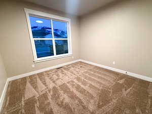 Carpeted spare room featuring baseboards