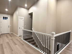 Hallway featuring an upstairs landing, light wood-style floors, and recessed lighting